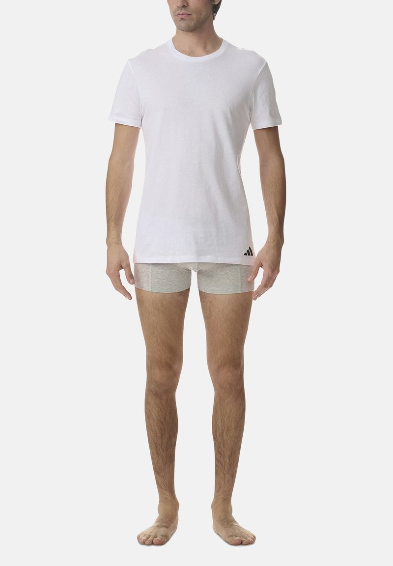 White crew-neck t-shirt made of cotton with short sleeves; paired with light grey boxer shorts. Minimal branding on shorts.