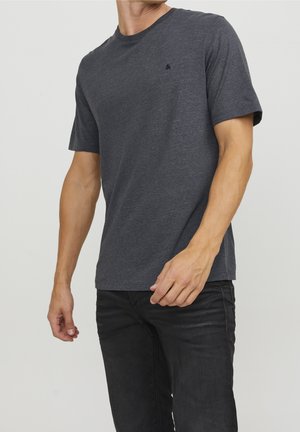 Gray short-sleeve t-shirt made of soft fabric. Features a crew neck and a small logo on the left chest. Worn with dark jeans.
