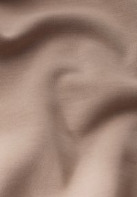 Tessuto marrone chiaro con una superficie liscia, caratterizzato da una sottile rigatura che crea dolci onde e variazioni di luce sulla superficie.