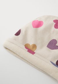 Bomullsmössa med beige bakgrund, prydd med flerfärgade hjärtmönster i rosa, lila och guld. Mjuk fleecefoder.