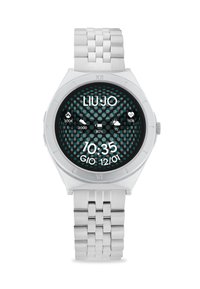 Reloj de metal plateado con una esfera redonda, que presenta un patrón de puntos en negro y turquesa. La pantalla digital muestra la hora y varios iconos.