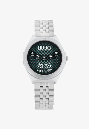 Reloj de metal plateado con una esfera redonda, que presenta un patrón de puntos en negro y turquesa. La pantalla digital muestra la hora y varios iconos.