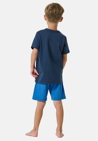 Granatowa koszulka z krótkim rękawem, zestawiona z niebiesko-białymi paskowanymi szortami, widok z tyłu. Miękki bawełniany materiał, casualowy styl.