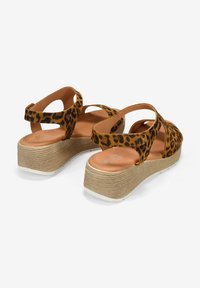 Sandalias de plataforma con estampado de leopardo y suela tejida texturizada. Diseño de tira cruzada ajustable en tonos marrón y marrón claro. Forro interior suave.
