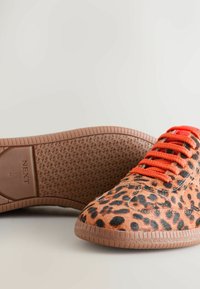 Leopardenmuster Sneaker mit orangefarbenen Schnürsenkeln, strukturiertem Kunstfell-Obermaterial und brauner Gummisohle mit einem strukturierten Profildesign.