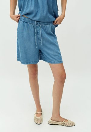Ljust blå denimshorts med resårmidja och dragsko, med sidofickor och avslappnat snitt, kombinerat med beige nät skor.