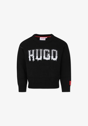 Pull en maille noir avec un col rond. Présente un logo "HUGO" blanc dégoulinant sur la poitrine et une étiquette de logo rouge sur la manche.