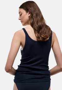 Débardeur bleu marine en texture côtelée avec bretelles fines, présentant une silhouette ajustée et des détails froncés à l'ourlet.