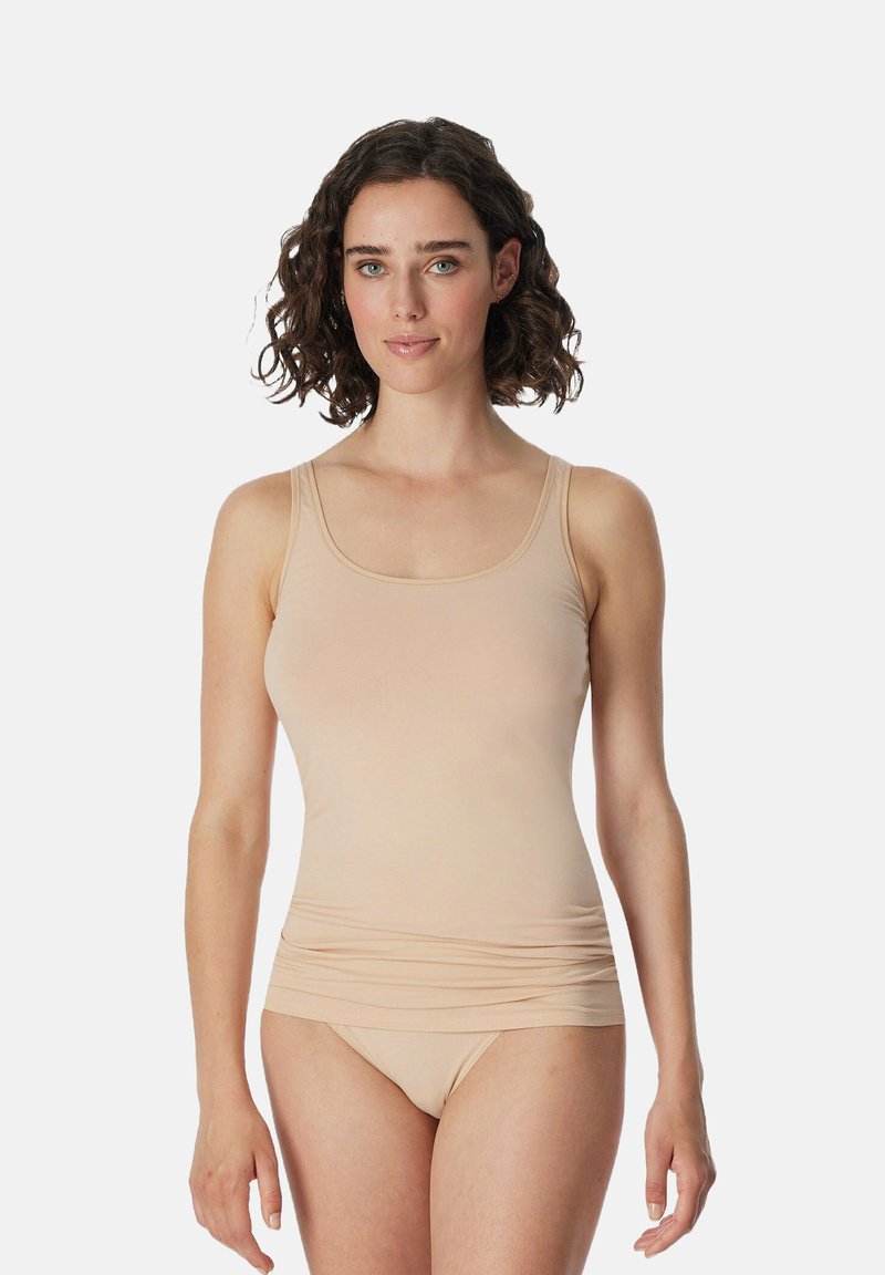 Canotta aderente beige con spalline larghe, texture morbida e dettaglio di tessuto arricciato in vita, abbinata a biancheria intima senza cuciture dello stesso colore.