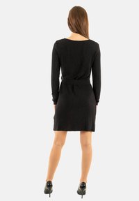 Abito nero a maniche lunghe con cintura in vita, tessuto uniforme, lunghezza al ginocchio, dotato di scollo rotondo e silhouette liscia e aderente.