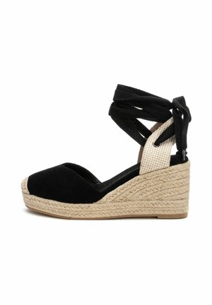 Sandalias de cuña de ante negro con plataforma de yute trenzado, que presentan correas de tela negra entrelazadas y una sección de tobillo texturizada en beige.
