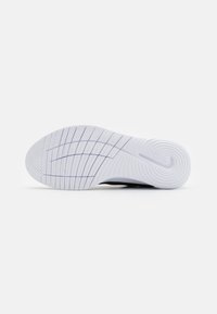Suola di sneaker bianca in gomma con scanalature orizzontali e verticali per una migliore aderenza, dotata di un discreto logo Nike impressa nell'area del tallone.