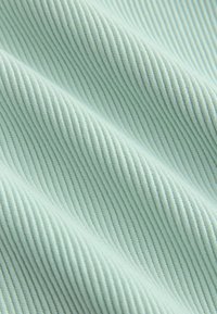 Šviesiai mėlyna ribuota medžiaga su minkštais raukšlėmis, rodanti arti esančią smulkių vertikalių briaunų tekstūrą.