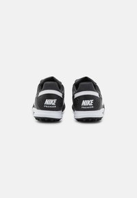 Zapatillas de deporte en negro y gris con una parte trasera texturizada, acentos blancos, suela gruesa y un destacado logo de Nike en el talón.