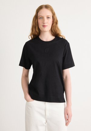 T-shirt in cotone nero con collo rotondo e maniche corte, caratterizzato da un logo testurizzato sottile sul petto. Design semplice e dritto.