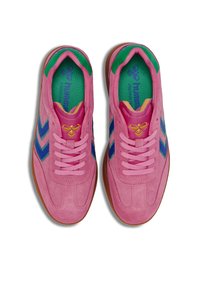 Rosa mockaskor med blå zickzack-ränder och gröna innersulor. Har matchande rosa snören och beige gummisålar.