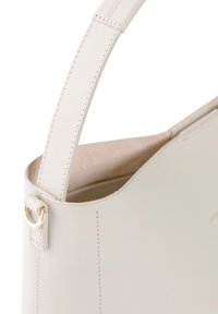 Cremfarbene Lederhandtasche mit glatter Textur, geschwungener Form, kurzem Tragegurt und goldenen Hardware-Akzenten. Innen hat sie eine weiche Oberfläche.