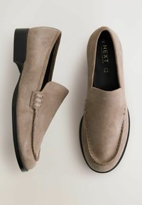 Mocassins en daim gris avec un petit talon noir, dotés d'une couture décorative sur le dessus et d'une doublure intérieure lisse.