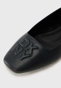 Juodas odinis butas batelis su tekstūriniu paviršiumi. Yra kvadratinė noselė ir įspaustas DKNY logotipas priekyje. Lygus vidinis pamušalas.