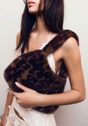 Geantă din blană artificială cu imprimeu de leopard, având o curea lată, cu o formă rotunjită și o textură moale, ținută aproape de purtătoare.