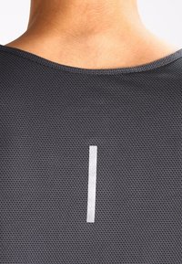 Tissu noir texturé avec un motif en maille, comportant une bande réfléchissante verticale au centre du dos, conçu pour les vêtements de sport.