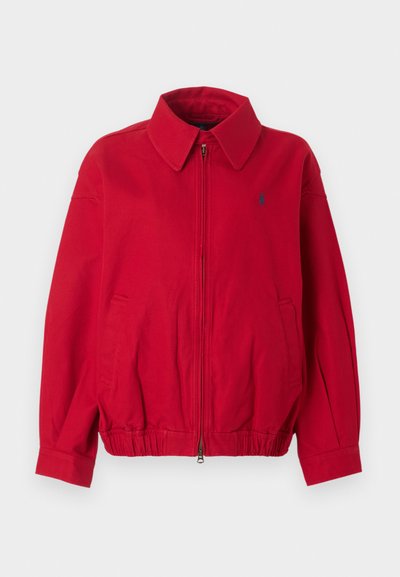 Κόκκινο τζάκετ με φερμουάρ και γιακά, ελαστική μέση, πλαϊνές τσέπες και μικρό σκούρο κεντητό λογότυπο στο αριστερό στήθος.