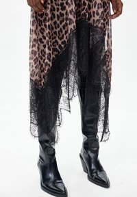 Sukienka w panterkę z czarną koronkową lamówką, przejrzystą tkaniną oraz czarne botki na słupku z ostrym noskiem. Teksturowane akcenty na krawędzi.