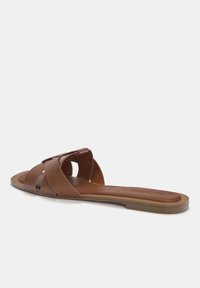 Ruske nahkaste klap sandals, millel on ristuvad rihmad ja lame alus. Omab tekstuurset viimistlust ja peent nupukest rihmal.