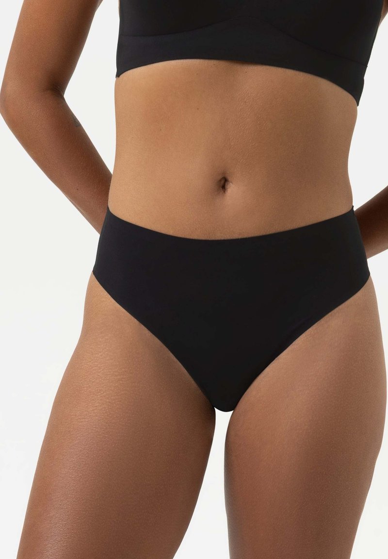 Culotte noire taille haute avec une texture lisse et extensible. Design sans couture et style minimaliste. Convient à différents types de corps.