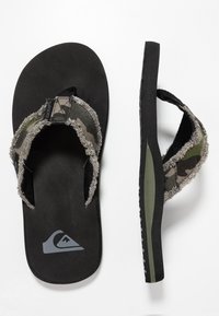 Infradito neri con cinturini in tessuto camo e suola testurizzata. Presenta un logo grigio sulla soletta e una costruzione robusta.