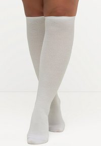Medias blancas hasta la rodilla, fabricadas en tela de punto acanalado, con una textura suave y un diseño ajustado, que se extienden justo debajo de la rodilla.
