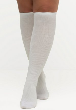 Chaussettes blanches jusqu'aux genoux en tissu tricoté côtelé, avec une texture lisse et un design ajusté, s'étendant juste en dessous du genou.