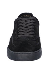 Black suede sneaker with black laces, rounded toe, and black rubber sole, viewed from the front on a white background.