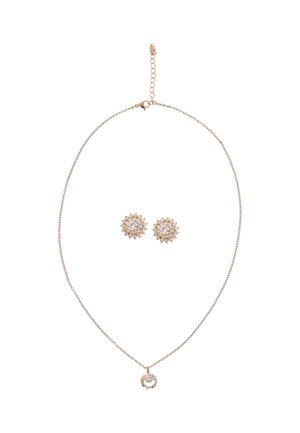 Roze gouden ketting met een cirkelvormige hanger en bijpassende stervormige oorbellen met heldere en amberkleurige kristallen. Lichtmetalen ketting.