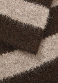 Gebreide stof met afwisselende strepen in donkerbruin en lichtbeige, met een zachte, textuurachtige afwerking en zichtbaar vezelmateriaal throughout.
