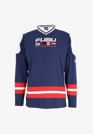 Hosszú ujjú tengerészkék jersey fehér részletekkel. A "FUBU" logó és nemzetközi zászlók láthatók rajta. Piros csíkok a szegélyen és az ujjakon. Texturált anyagból készült.