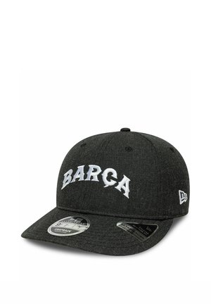 Czarna czapka z daszkiem snapback z białym napisem "BARÇA" z przodu i logo New Era z boku, z dwoma naklejkami produktowymi na daszku.