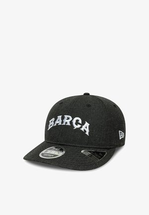 Czarna czapka z daszkiem snapback z białym napisem "BARÇA" z przodu i logo New Era z boku, z dwoma naklejkami produktowymi na daszku.