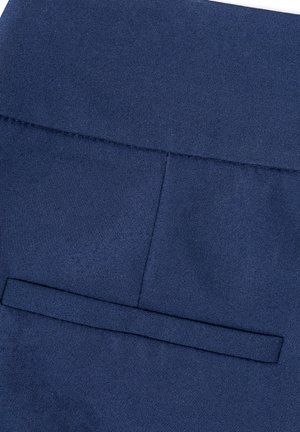 Zbliżenie na granatową tkaninę z poziomą kieszenią z patką i detalem przeszycia w pasie.