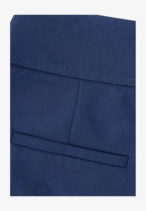 Zbliżenie na granatową tkaninę z poziomą kieszenią z patką i detalem przeszycia w pasie.