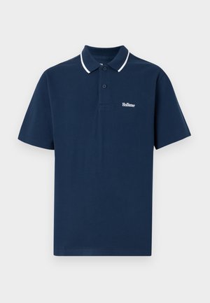 Navy blue short-sleeve polo shirt made of cotton. Features a collar with white trim and a small white logo on the left chest area.