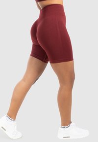 Bordeaux hoge taille shorts met een textuurpatroon en gladde stof, met een getailleerd ontwerp en een lengte tot halverwege de dij. Te combineren met witte sneakers.