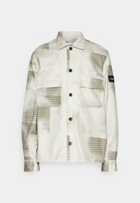 Chaqueta ligera con patrón a cuadros que presenta dos bolsillos frontales, botones negros y un sutil parche con logo en la manga en tonos beige y oliva.