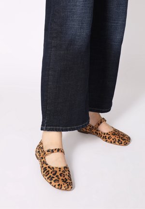 Zapatos planos con estampado de leopardo en beige y marrón, con punta puntiaguda y correa en el tobillo con hebilla. Combinados con jeans de pierna ancha en azul oscuro.