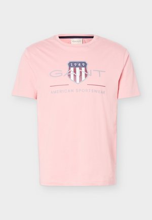 Hele-roosa lühikeste varrukatega T-särk GANT logo, kilbiembleemiga, millel on aastaarv „1949“ ja tekst „American Sportswear“ ees.