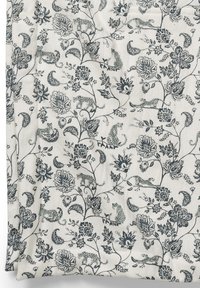 Blommönstrad tyg i krämfärg med mörkblå och gröna accenter, som visar detaljerade djur mellan olika blommor och blad. Texturerad yta.