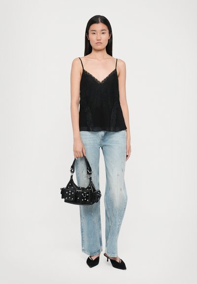 Camisole noir avec des détails en dentelle, associé à un jean léger bleu déchiré et un petit sac à main noir avec des accents en argent. Mules noires à talons.