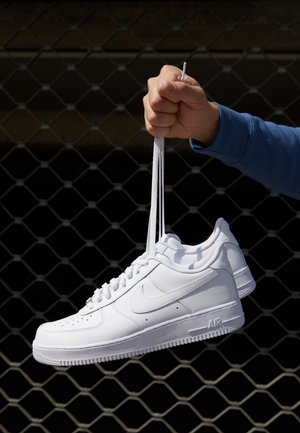 Weiße Leder-Sneaker mit Perforationen, runder Zehenpartie, flacher Sohle und dicken Schnürsenkeln, mit sichtbar eingesticktem Swoosh-Logo und "AIR" an der Ferse.