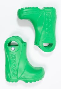 Bottes en caoutchouc vertes avec des surfaces texturées, des orteils arrondis et des trous latéraux pour la ventilation. Comprend un logo en relief et des semelles texturées pour une meilleure adhérence.