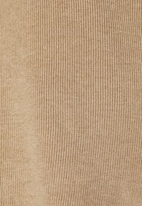 Tissu beige côtelé avec une texture fine, présentant des rayures verticales serrées et une finition lisse, adapté à divers vêtements.